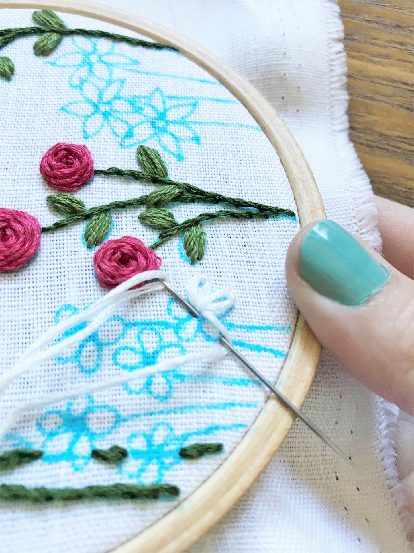 Family Flower Garden Kit in progress. Roses have been completed. Daisies are being stitched in white on white linen background with blue pen pattern.