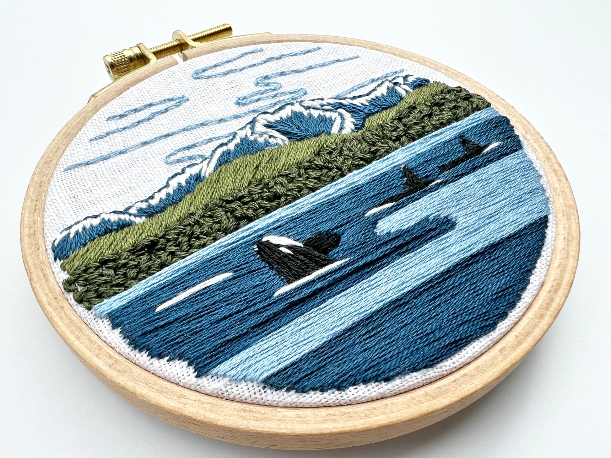 Orcas in the Sound Hand Embroidery PDF.  File includes pattern for transfer and booklet with easy to follow step by step instructions.  Part of the Pacific Wanderlust Collection.  Three Orcas swimming with Mountains in the background.