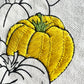 Yellow stitch detail of Bell Pepper on Meet me at the Market canvas tote bag.  bright yellow stitches define the body of the pepper while black stitching reinforces the outlines and curves.