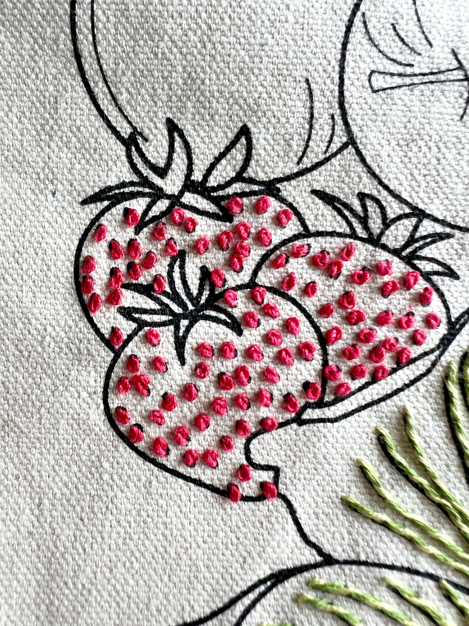 Strawberries on Meet me at the Market tote showing stitch detail of red seeds. Heavy cream canvas with screen printed black outline of strawberries.