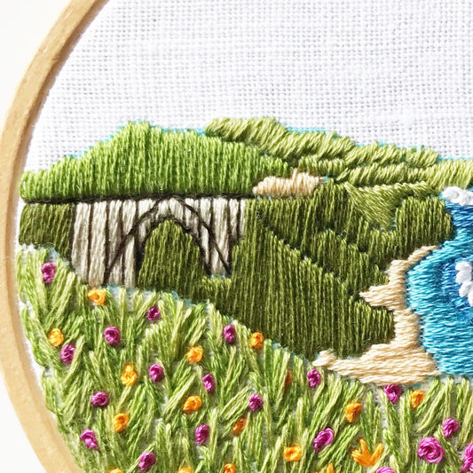 Big Sur California Hand Embroidery PDF. 13 page booklet gives easy to follow directions to complete this oceanside Modern Embroidery.  Flowers in the foreground with HWY 101 Big Sur Bridge in the background.  White waves crashing on beach.