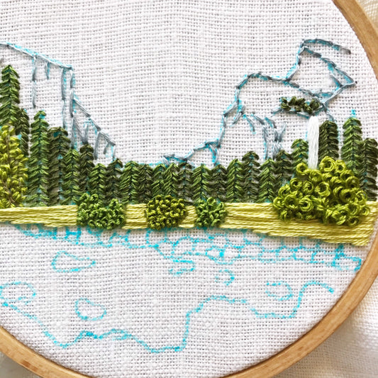 Close up of Yosemite Hand Embroidery in progress.  Blue marker denotes next stitch location while mountains, trees and bushes are complete.