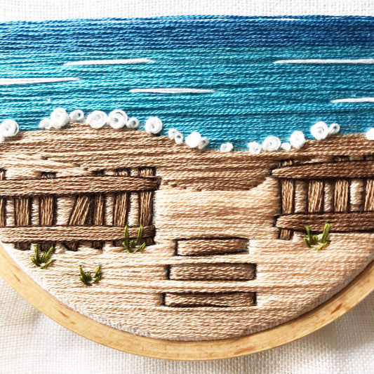 Close up of Intermediate Embroidery Kit , A Day at the Beach.  Shows stitch detail in browns, blues, white and green embroidery floss.